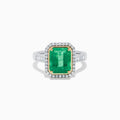 The Brasilica 14K Two Tone Gold Emerald and Diamond Ring showcases a large rectangular green emerald in a gold prong setting, accented by a halo of clear diamonds and baguette-cut diamonds along the band.