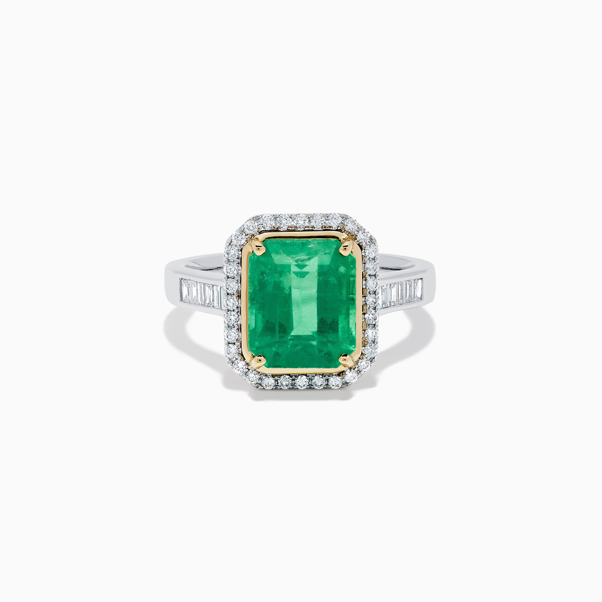 The Brasilica 14K Two Tone Gold Emerald and Diamond Ring showcases a large rectangular green emerald in a gold prong setting, accented by a halo of clear diamonds and baguette-cut diamonds along the band.