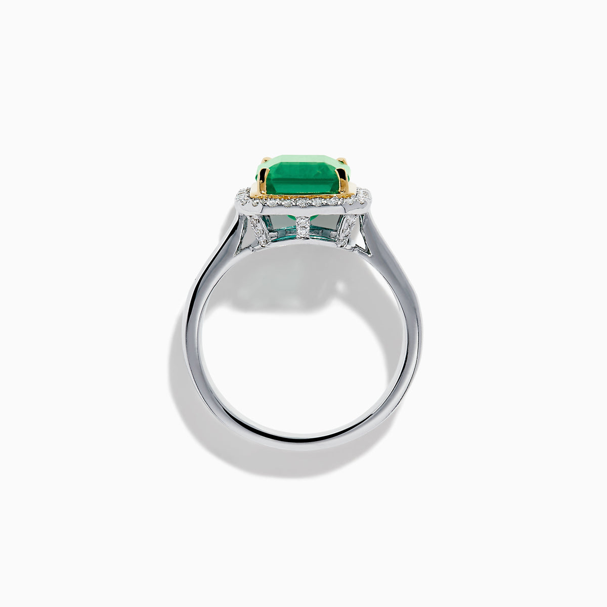 The Brasilica 14K Two Tone Gold Emerald and Diamond Ring showcases a large rectangular green emerald in a gold prong setting, accented by a halo of clear diamonds and baguette-cut diamonds along the band.