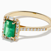 The 14K Yellow Gold Emerald and Diamond Ring showcases a rectangular emerald center stone, accented by white diamonds around the gemstone and along the band.