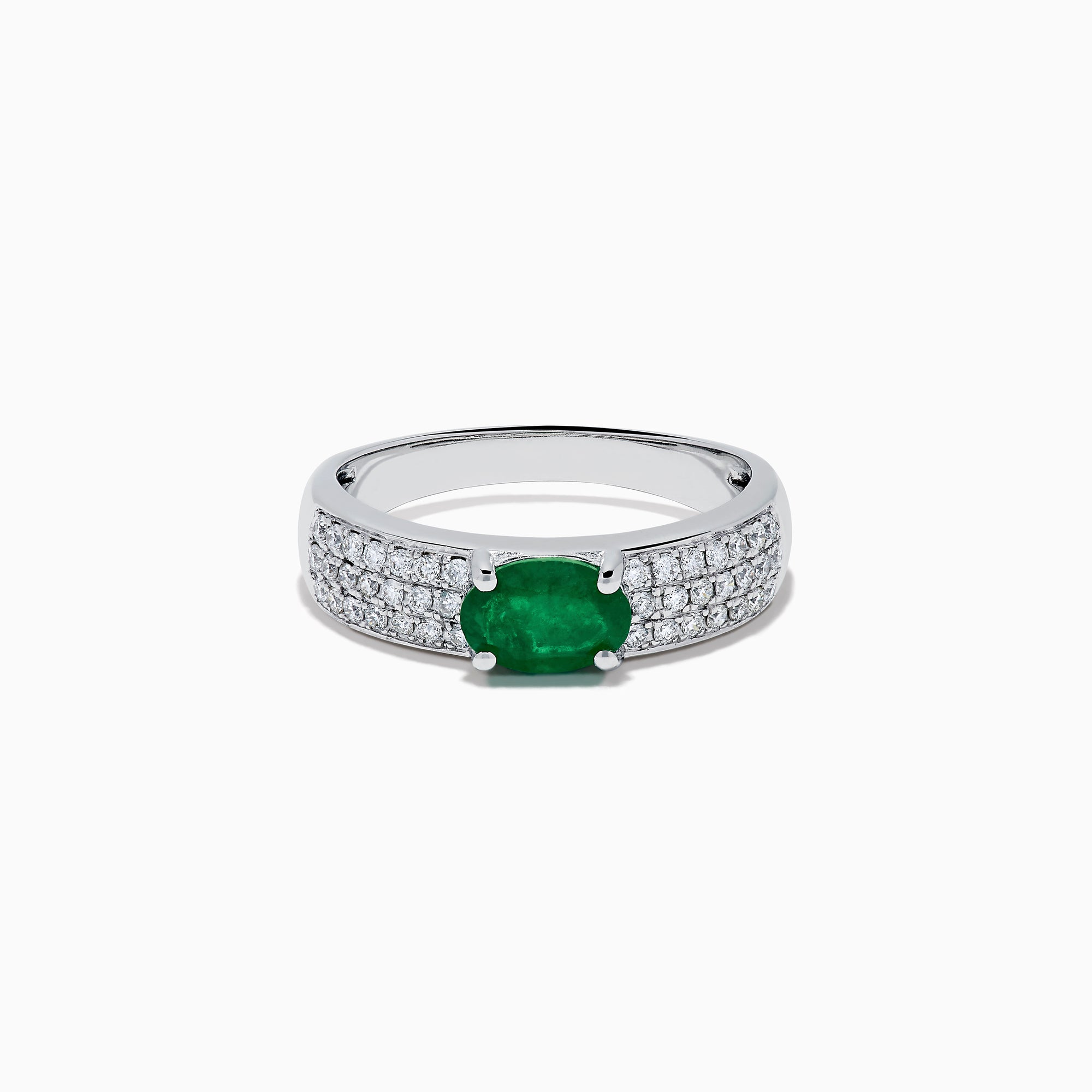 The Brasilica 14K White Gold Emerald and Diamond Ring showcases a central oval green emerald with three rows of round diamonds on each side, set in white gold and shown against a white background.