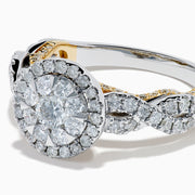 The 14K Two Tone Gold Diamond Cluster Engagement Ring features a central round diamond cluster, surrounded by a halo of smaller diamonds on an intricately designed band embellished with more diamonds.