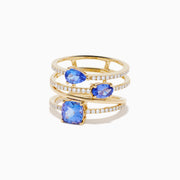 The 14K Yellow Gold Tanzanite and Diamond Multi-Row Statement Ring features three stacked bands set with white diamonds and pear, oval, and cushion-cut blue tanzanite gemstones.