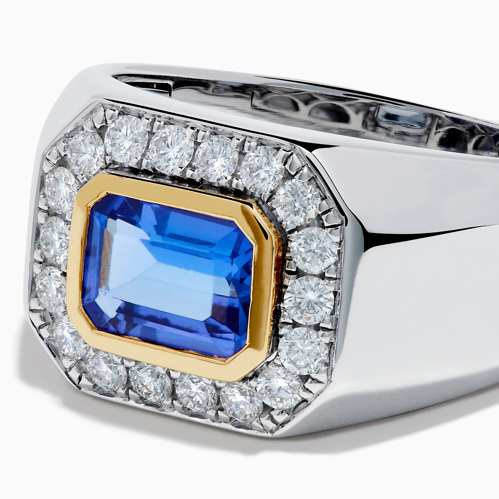 The Men's 14K Two Tone Gold East West Emerald Cut Tanzanite and Diamond Ring features a rectangular blue tanzanite set in a gold bezel, framed by white diamonds, all beautifully crafted against a plain white background.