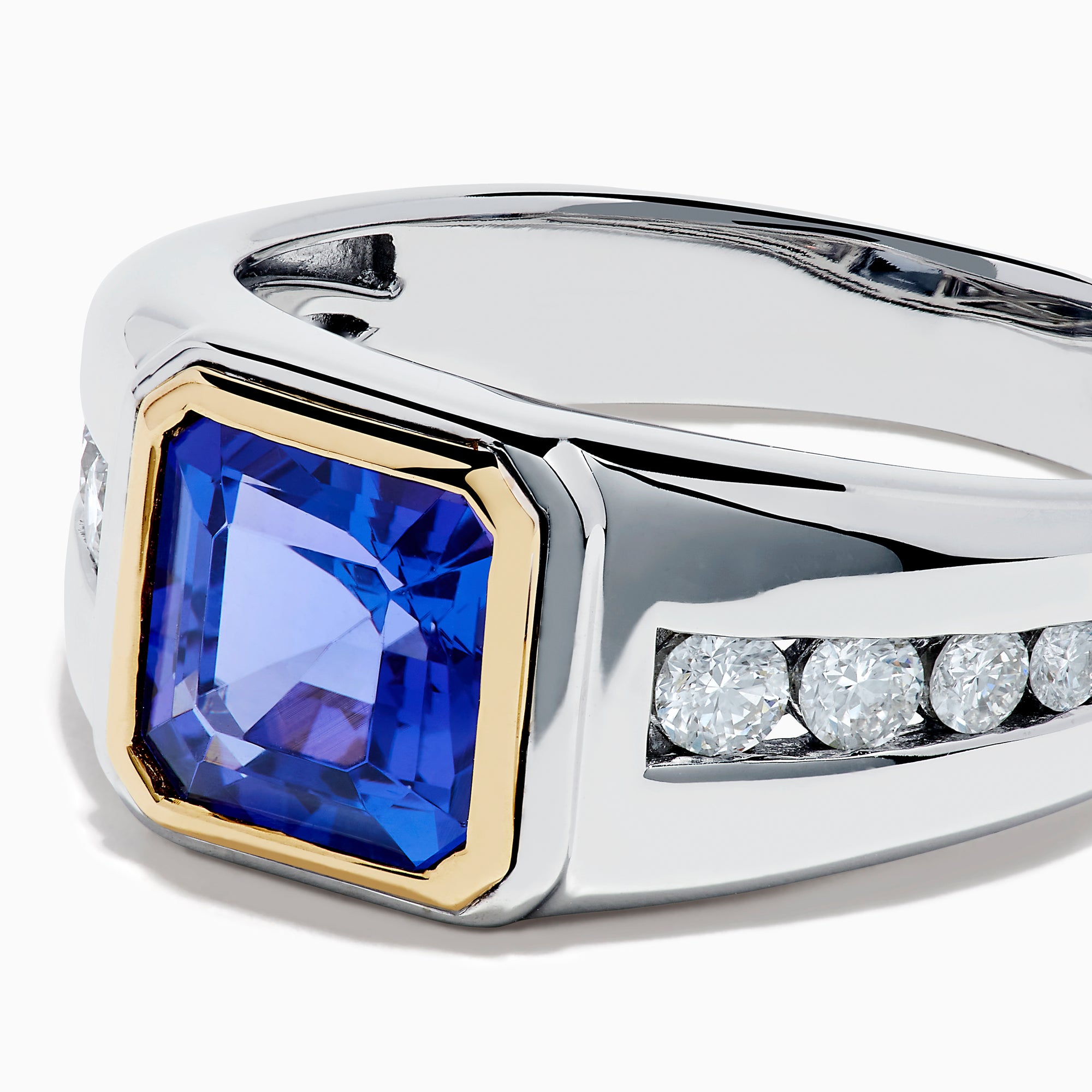 The Men's 14K Two Tone Gold Bezel Set Tanzanite and Diamond Signet Ring features a bold square tanzanite center, bordered by a gold bezel, and accented with small round diamonds on each side of the band.