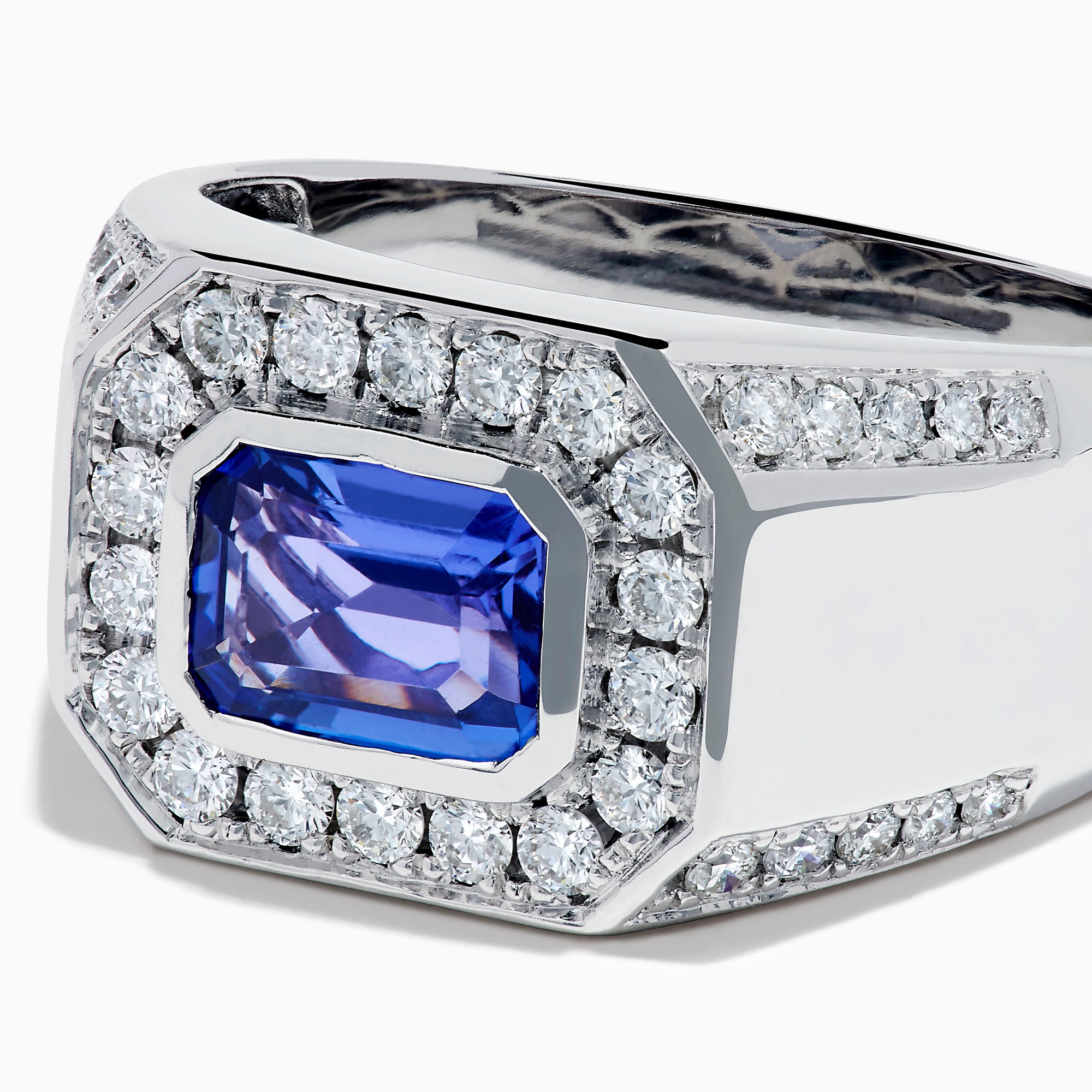 The Men's 14K White Gold East West Tanzanite and Diamond Signet Ring features a rectangular tanzanite center set among round diamonds in a bold geometric design, showcased on a white background.