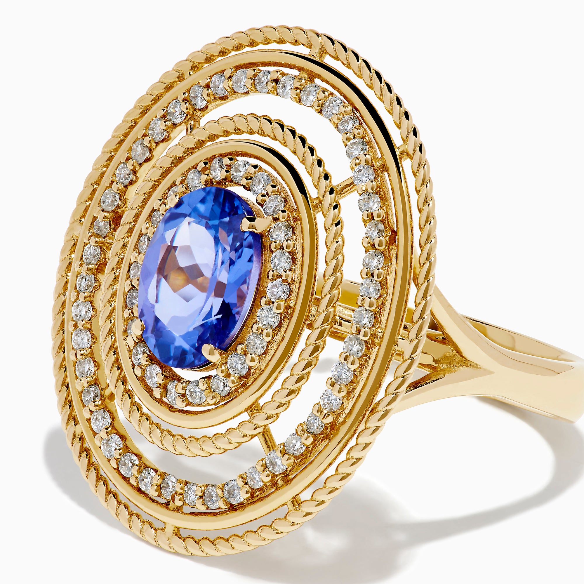 The 14K Yellow Gold Tanzanite and Diamond Concentric Halo Ring showcases concentric circular diamond bands with a central oval tanzanite gemstone, elegantly presented on a white background.