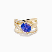The 14K Yellow Gold Tanzanite and Diamond Crossover Ring showcases an oval tanzanite center stone accented by intersecting diamond-encrusted bands for a brilliant, modern look.