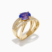 The 14K Yellow Gold Tanzanite and Diamond Crossover Ring showcases an oval tanzanite center stone accented by intersecting diamond-encrusted bands for a brilliant, modern look.