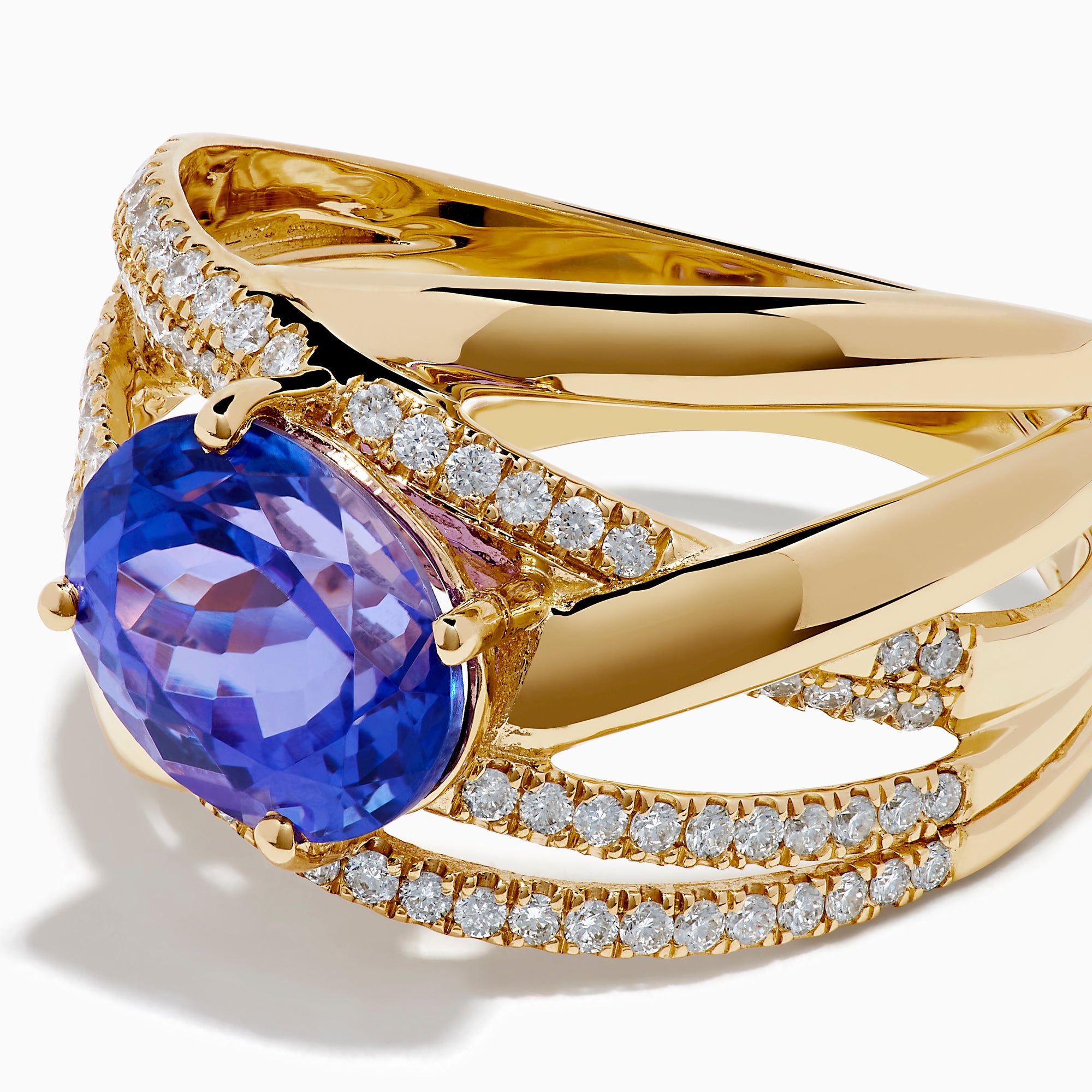 The 14K Yellow Gold Tanzanite and Diamond Crossover Ring showcases an oval tanzanite center stone accented by intersecting diamond-encrusted bands for a brilliant, modern look.