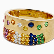 The Watercolors 14K Yellow Gold Multi Sapphire and Diamond Scattered Wide Band showcases vibrant sapphires and sparkling diamonds artfully scattered across a bold yellow gold band for a colorful, eye-catching look.