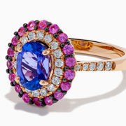 The 14K Rose Gold Tanzanite, Diamond, and Pink Sapphire Oval Halo Ring features a large oval blue tanzanite center, double halos of white diamonds and pink sapphires, plus diamond accents on the band.