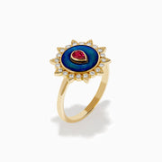 The 14K Yellow Gold Ruby, Diamond, and Enamel Ring showcases a central teardrop ruby, a blue enamel circle, and an outer border of round diamonds in a sunburst design.