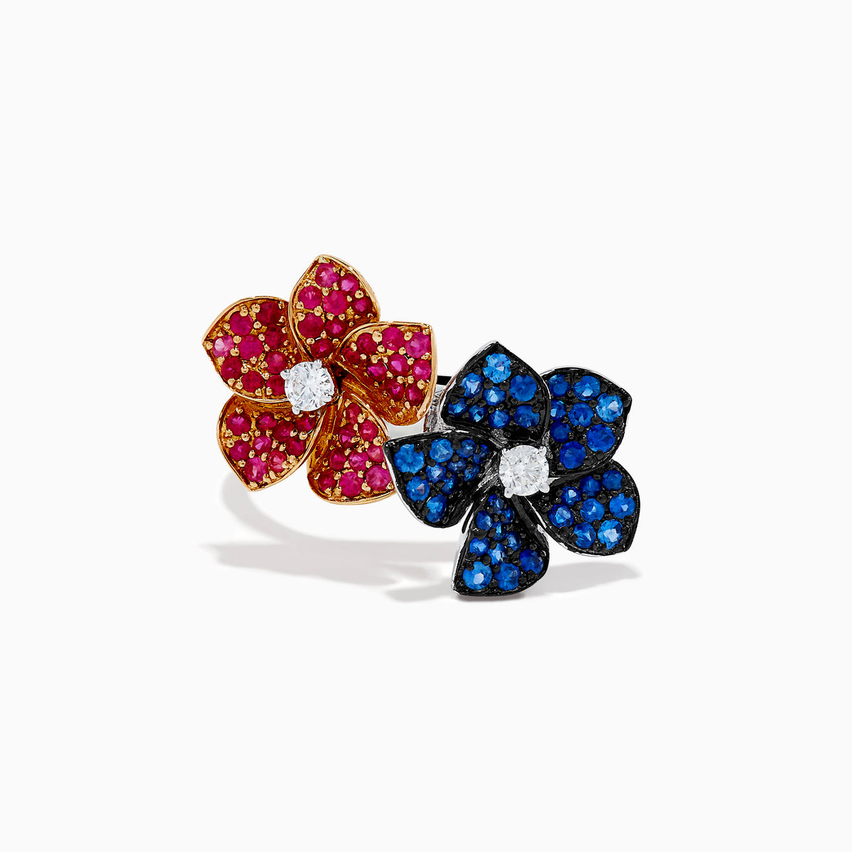 The 14K Two Tone Ruby, Sapphire, and Diamond Floral Bypass Ring features jeweled floral designs with ruby, sapphire, and diamond accents, displayed elegantly on a white background.