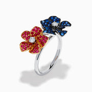 The 14K Two Tone Ruby, Sapphire, and Diamond Floral Bypass Ring features jeweled floral designs with ruby, sapphire, and diamond accents, displayed elegantly on a white background.