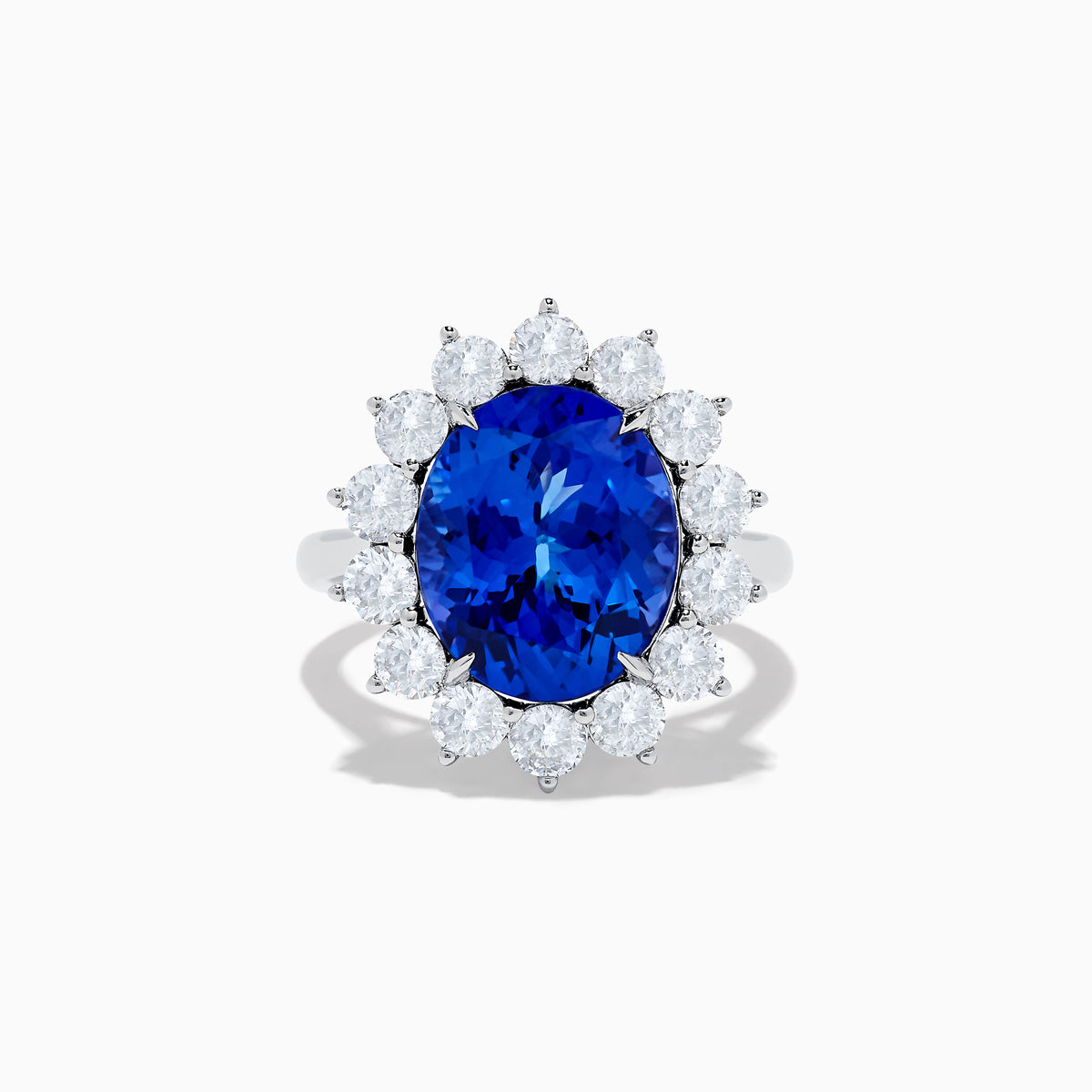 The Hematian 14K White Gold Tanzanite and Diamond Ring showcases a striking oval blue tanzanite center with a halo of round white diamonds, displayed on a plain white background.