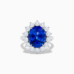 The Hematian 14K White Gold Tanzanite and Diamond Ring showcases a striking oval blue tanzanite center with a halo of round white diamonds, displayed on a plain white background.
