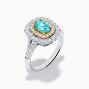 The 18K Two Tone Gold Paraiba and Diamond Double Halo Ring features an oval Paraiba centerpiece, surrounded by radiant yellow and white diamonds in a double halo, creating a striking layered effect.