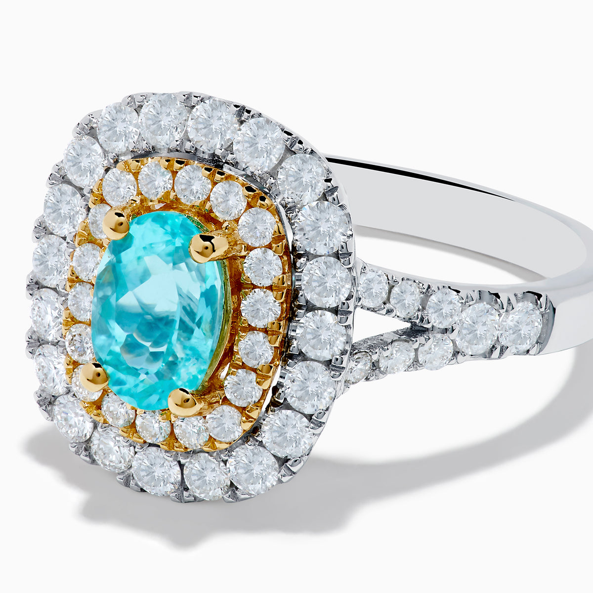 The 18K Two Tone Gold Paraiba and Diamond Double Halo Ring features an oval Paraiba centerpiece, surrounded by radiant yellow and white diamonds in a double halo, creating a striking layered effect.