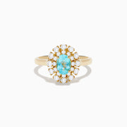 The 18K Yellow Gold Paraiba and Diamond Ring features an oval Paraiba gemstone at the center, encircled by a double halo of round diamonds, all showcased on a plain white background.