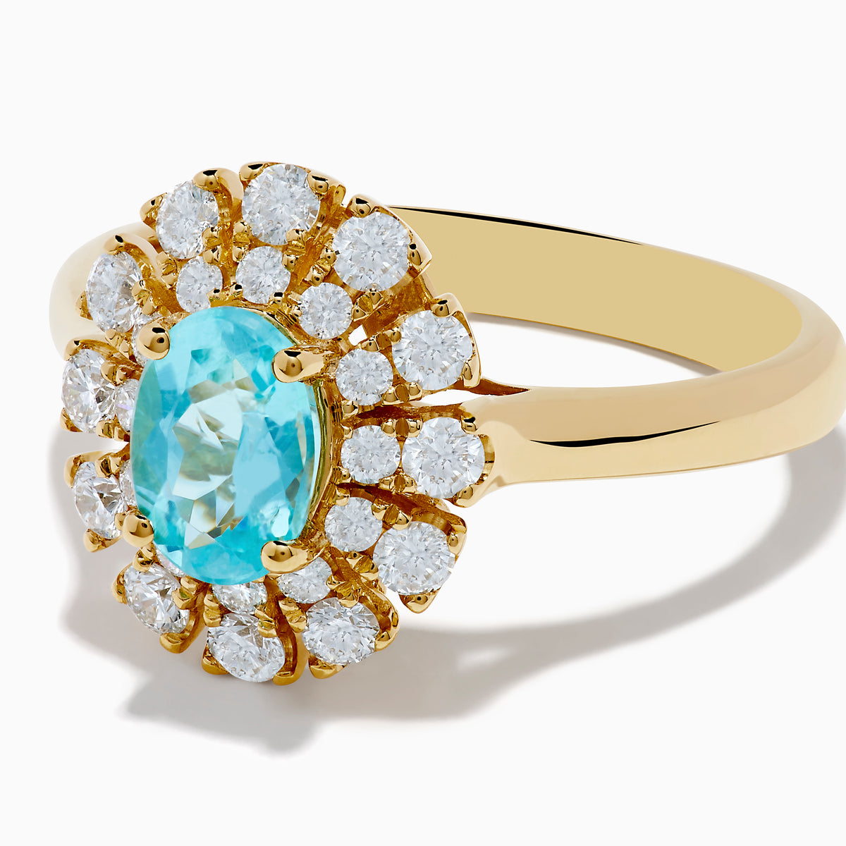 The 18K Yellow Gold Paraiba and Diamond Ring features an oval Paraiba gemstone at the center, encircled by a double halo of round diamonds, all showcased on a plain white background.