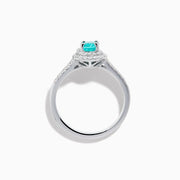 The 18K White Gold Paraiba and Diamond Ring showcases an oval Paraiba gemstone at the center, encircled by a halo of sparkling diamonds and accented with additional diamonds along its elegant split shank band.