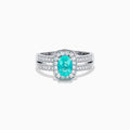 The 18K White Gold Paraiba and Diamond Halo Ring features an oval Paraiba center gemstone, encircled by sparkling diamonds and set on an elegant split shank band adorned with additional diamonds.