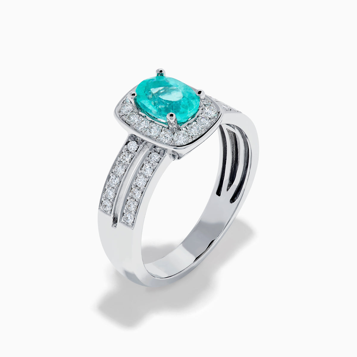 The 18K White Gold Paraiba and Diamond Halo Ring features an oval Paraiba center gemstone, encircled by sparkling diamonds and set on an elegant split shank band adorned with additional diamonds.