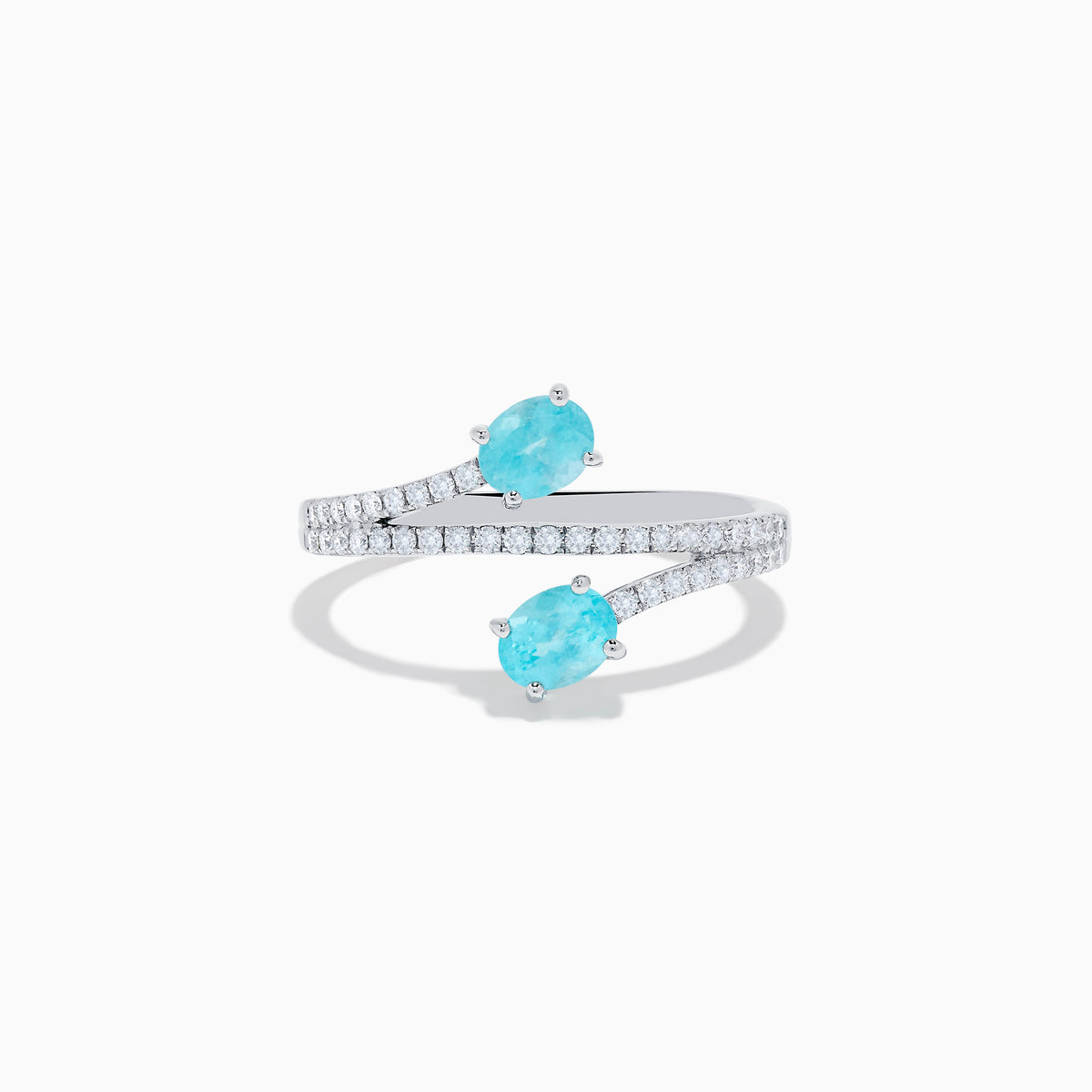 The 18K White Gold Paraiba and Diamond Bypass Ring features two oval Paraiba gemstones at each end of an open band, accented with small sparkling diamonds along the upper surface.