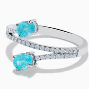 The 18K White Gold Paraiba and Diamond Bypass Ring features two oval Paraiba gemstones at each end of an open band, accented with small sparkling diamonds along the upper surface.