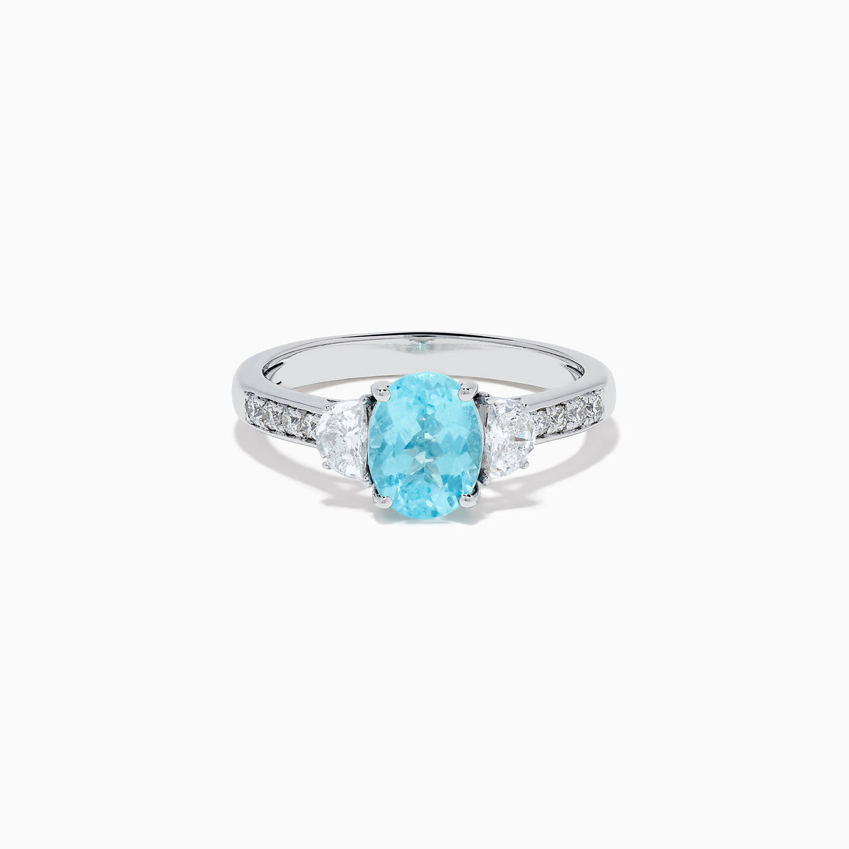 The 14K White Gold Paraiba and Diamond Three Stone Ring features an oval blue Paraiba at the center, flanked by two diamonds, with additional diamonds set along each side of the band.