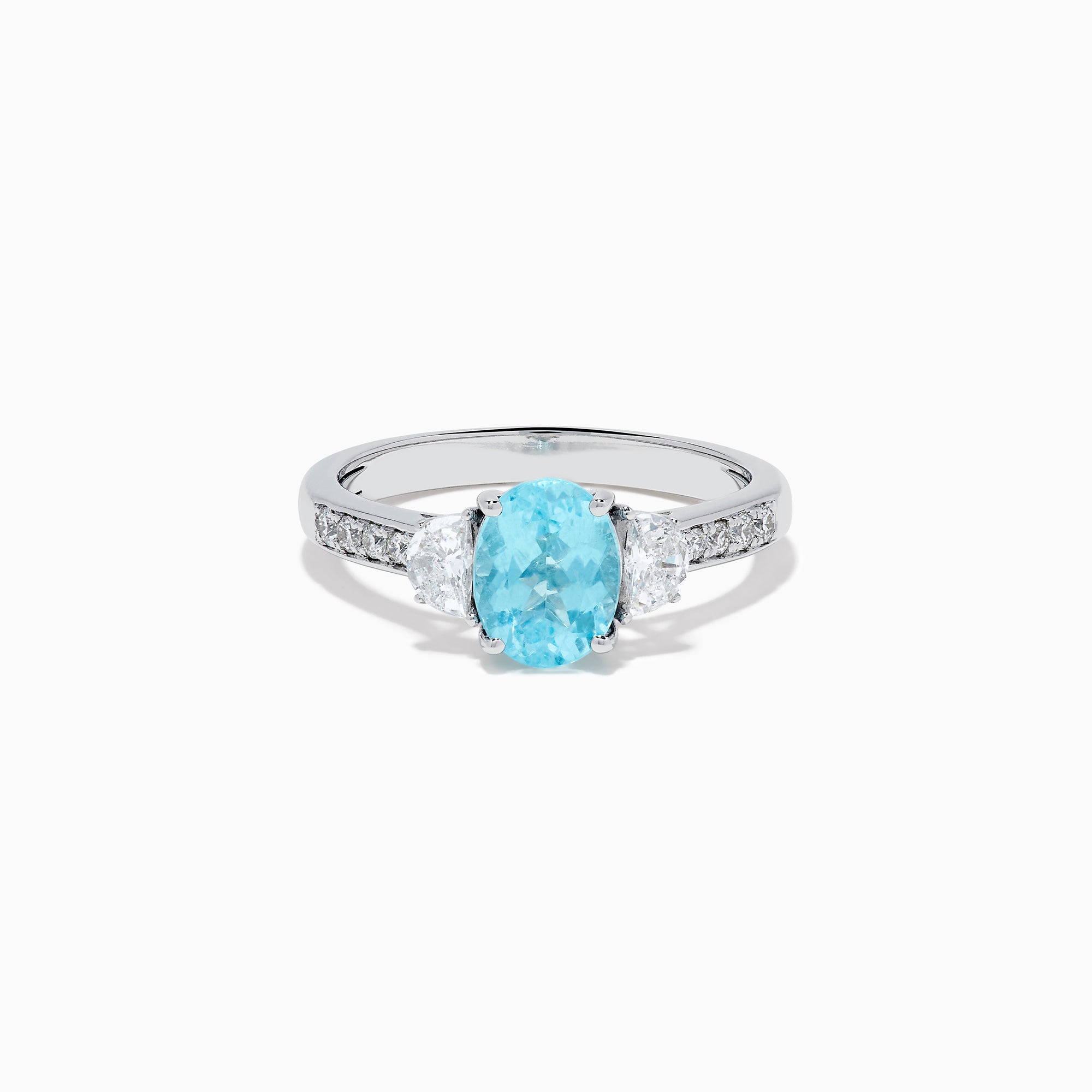 The 14K White Gold Paraiba and Diamond Three Stone Ring features an oval blue Paraiba at the center, flanked by two diamonds, with additional diamonds set along each side of the band.