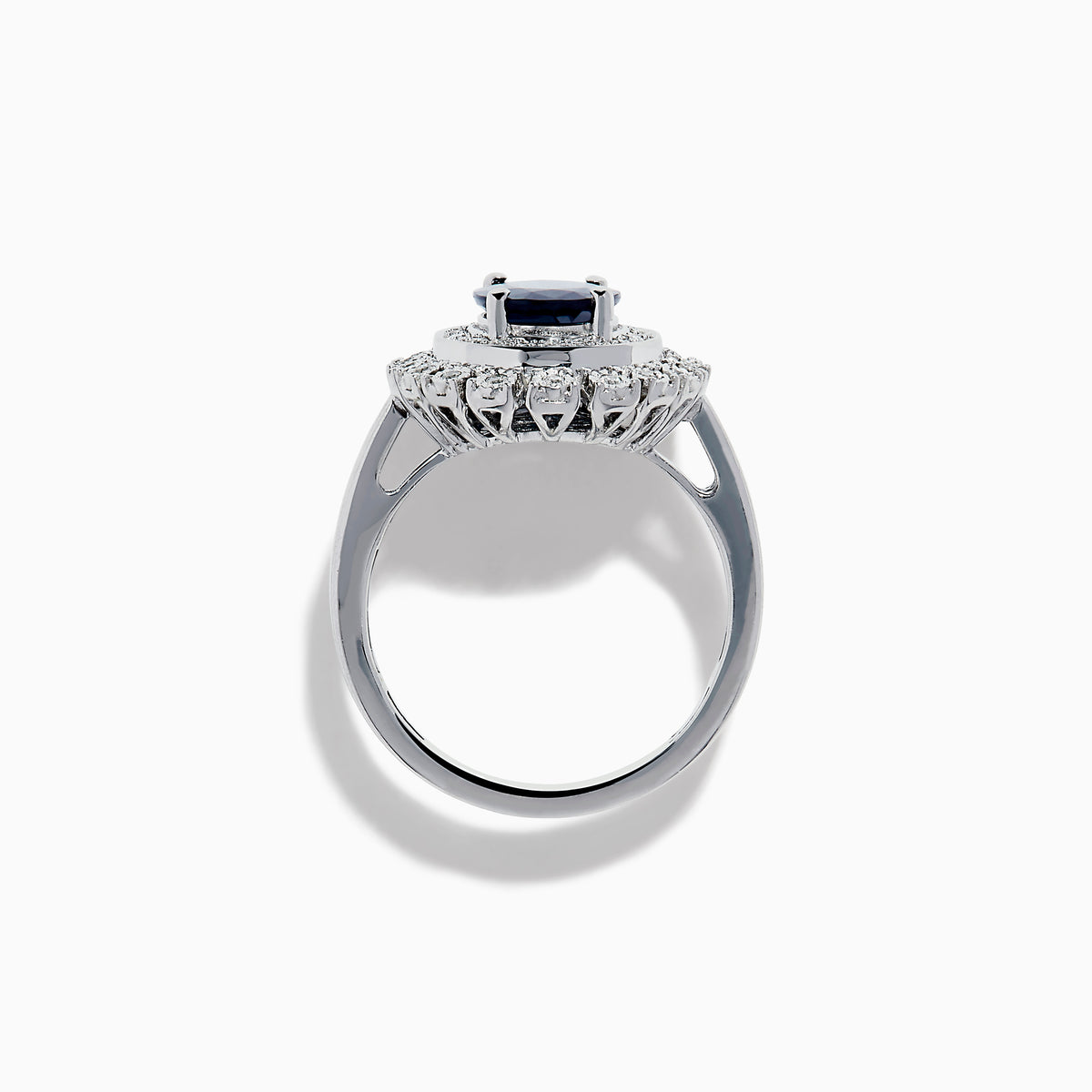 The 14K White Gold Blue Sapphire and Diamond Double Halo Ring features an oval blue sapphire surrounded by two halos of round white diamonds on a white gold band, shown against a white background.