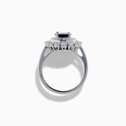 The 14K White Gold Blue Sapphire and Diamond Double Halo Ring features an oval blue sapphire surrounded by two halos of round white diamonds on a white gold band, shown against a white background.