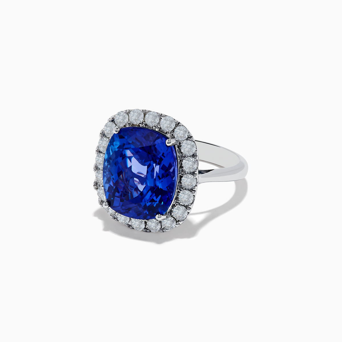 The Nahla Siri 14K White Gold Tanzanite and Diamond Ring showcases a large cushion-cut blue tanzanite center, encircled by a halo of round white diamonds, shown on a white background.