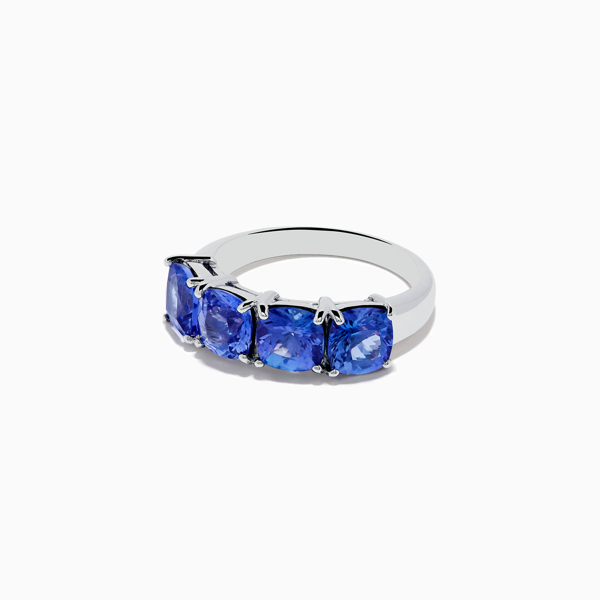 The Nahla Siri 925 Silver Tanzanite Ring showcases four large, cushion-cut blue gemstones set in a row, elegantly displayed on a plain white background.