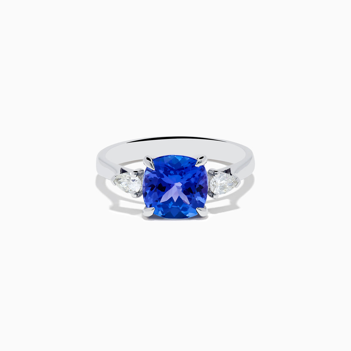 The Nahla Siri 14K White Gold Tanzanite and Diamond Ring features a large cushion-cut blue tanzanite center stone, accented by two smaller white diamonds on each side, set against a white background.