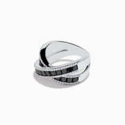 The 14K White Gold Black and White Diamond Crossover Ring features intersecting bands set with rectangular black and white diamonds, accented by rows of small clear stones for a striking crisscross effect.