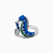 The Seaside 14K White Gold Blue Sapphire and Diamond Seahorse Ring features two seahorses with blue and green enamel details and sparkling gemstones, shown against a white background.