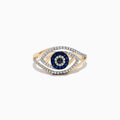 The Novelty 14K Yellow Gold Blue Sapphire and Diamond Evil Eye Ring showcases an eye-shaped design with a central blue sapphire, surrounded by blue and clear stones, and finished with an outer layer of diamonds forming the eye outline.