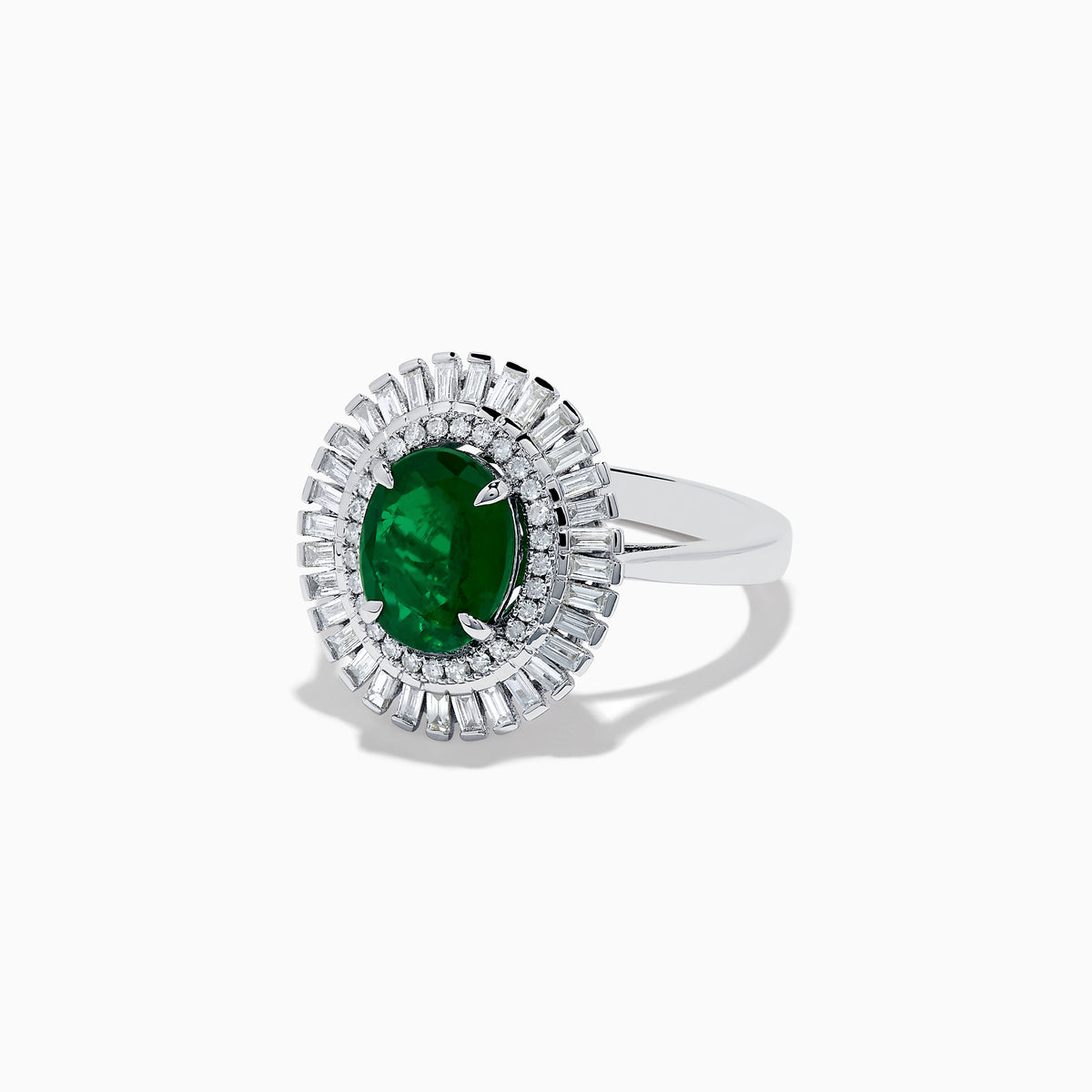 The 14K White Gold Emerald and Diamond Ring features an oval emerald center accented by two rows of baguette and round diamonds in a radiant halo design.
