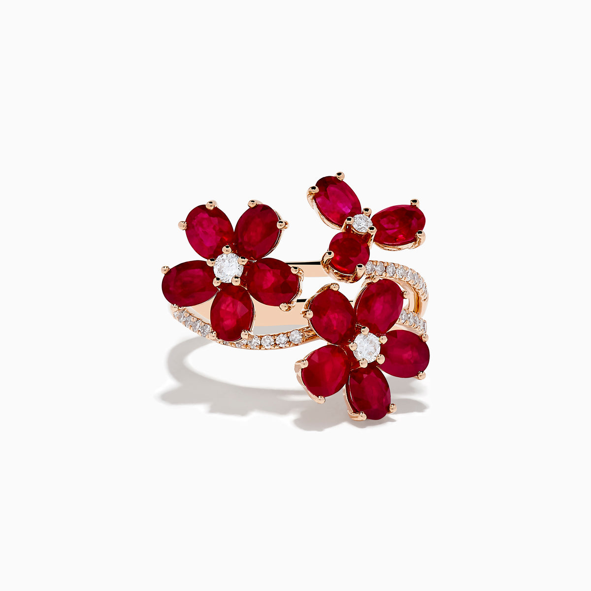 The Ruby Royale 14K Rose Gold Ruby Flower Cocktail Ring features three red ruby flower accents with diamond centers and encrusted leaves, all displayed on a white background.