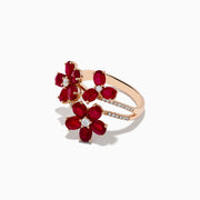 The Ruby Royale 14K Rose Gold Ruby Flower Cocktail Ring features three red ruby flower accents with diamond centers and encrusted leaves, all displayed on a white background.