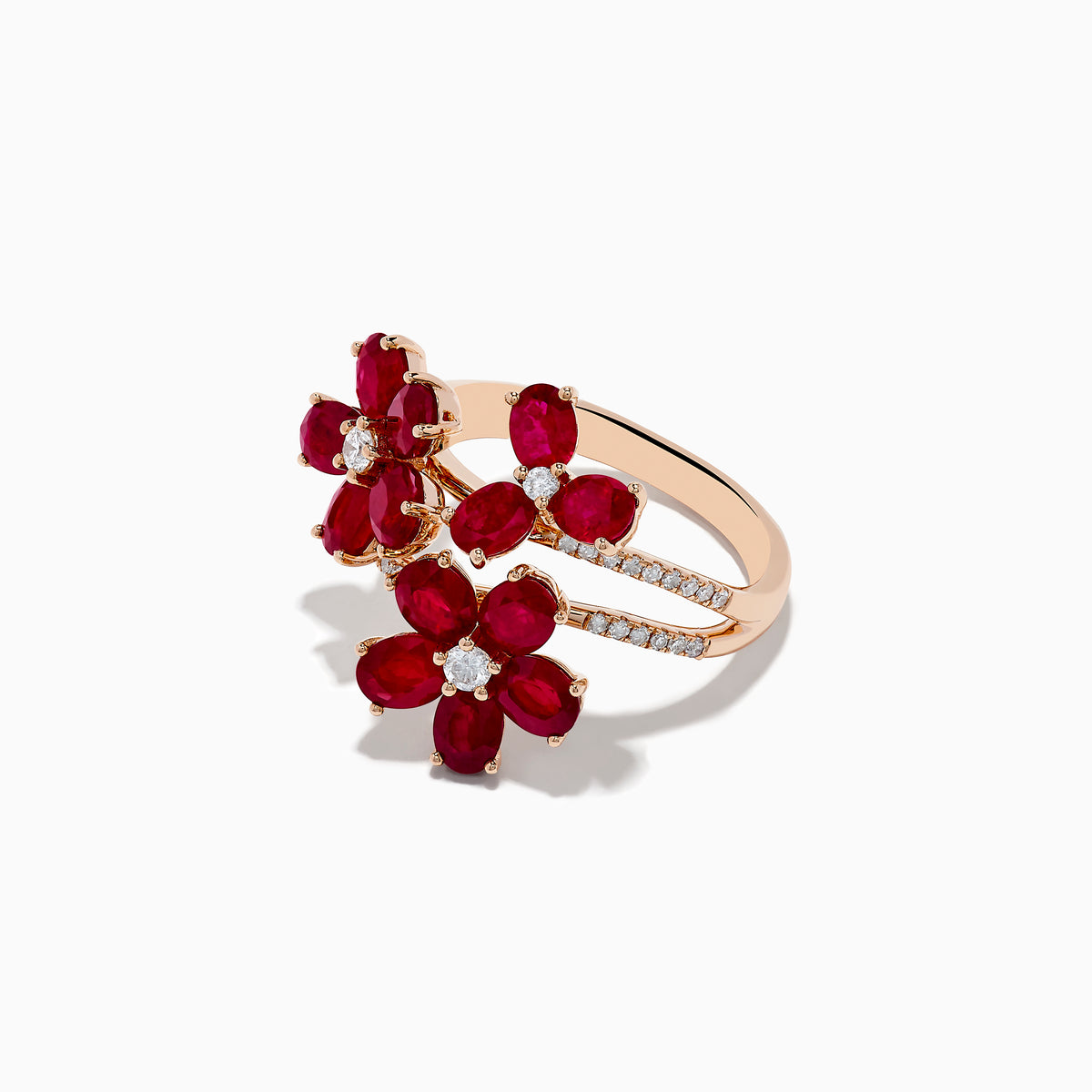 The Ruby Royale 14K Rose Gold Ruby Flower Cocktail Ring features three red ruby flower accents with diamond centers and encrusted leaves, all displayed on a white background.