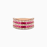The 14k Rose Gold Princess Cut Pink Tourmaline and Ruby Ring 1.61 TCW features three rows of square pink stones and rubies, bordered by sparkling clear stones, all set in a wide band with a white backdrop.