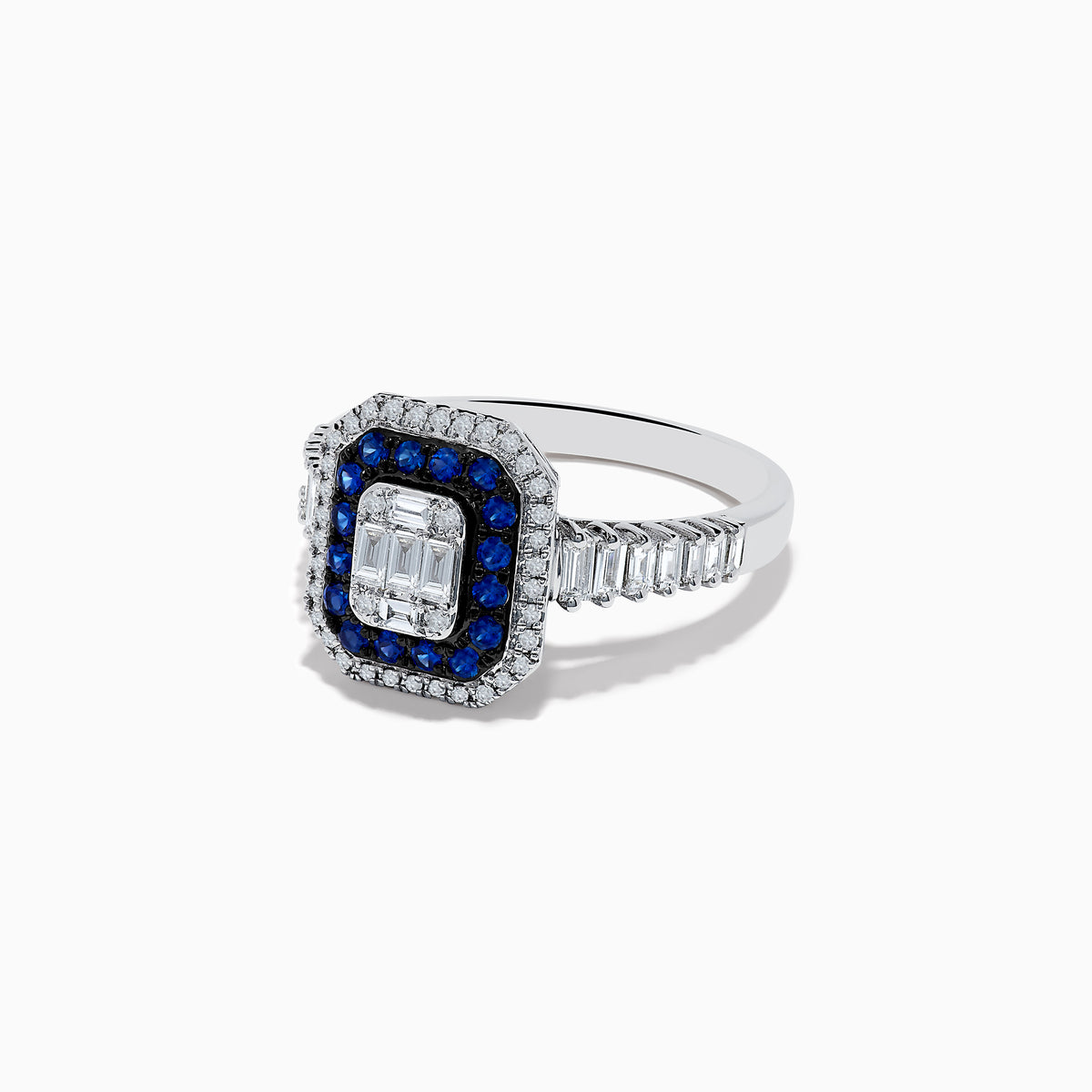 The Royale Bleu 14K White Gold Blue Sapphire and Diamond Ring showcases a rectangular center diamond, encircled by a blue sapphire halo, a second white diamond halo, and baguette-cut diamonds on the band.
