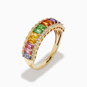 The Watercolors 14K Yellow Gold Multi Sapphire Baguette Band Ring showcases a row of rectangular rainbow sapphires, bordered by small round clear stones for a vibrant, elegant look.