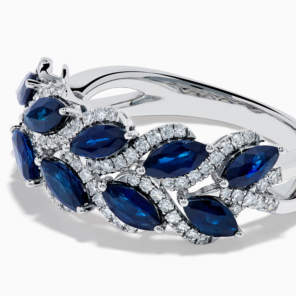 The 14K White Gold Sapphire and Diamond Leaf Motif Ring features alternating marquise-shaped blue sapphires and small round diamonds arranged in a woven, leaf-like design.
