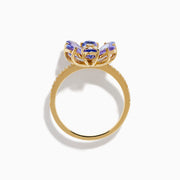 The Nahla 14K Yellow Gold Tanzanite and Diamond Flower Ring features six tanzanite petals, a center cluster of white diamonds, and extra diamonds set along the band for added sparkle.