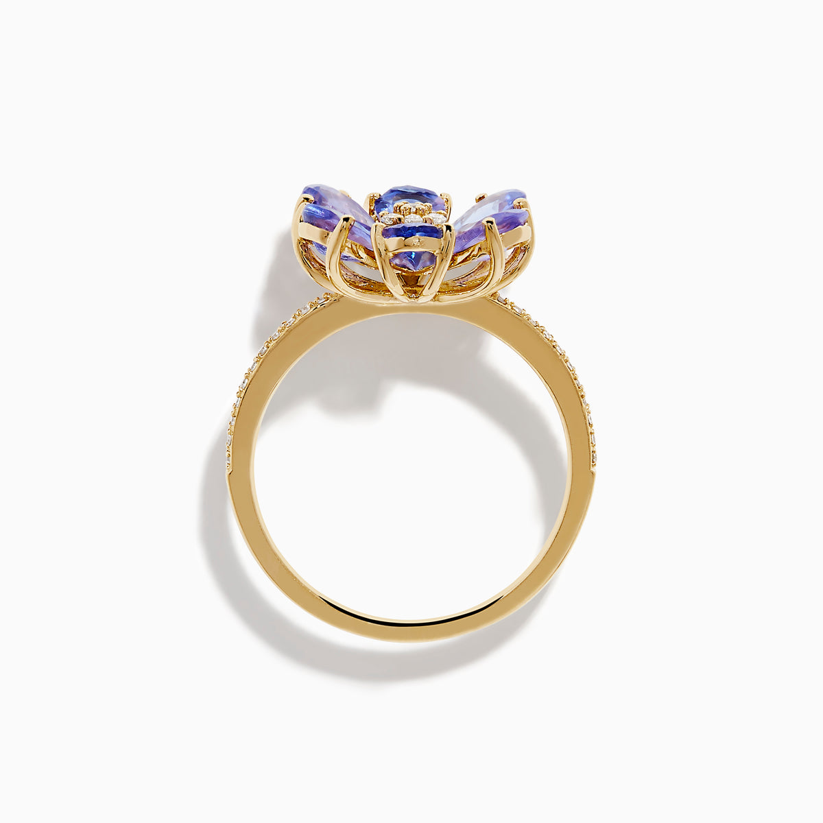 The Nahla 14K Yellow Gold Tanzanite and Diamond Flower Ring features six tanzanite petals, a center cluster of white diamonds, and extra diamonds set along the band for added sparkle.